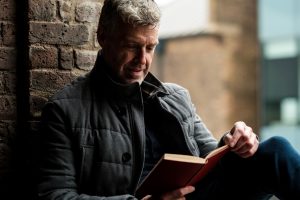 Grey-haired man reading a book enjoying his free time